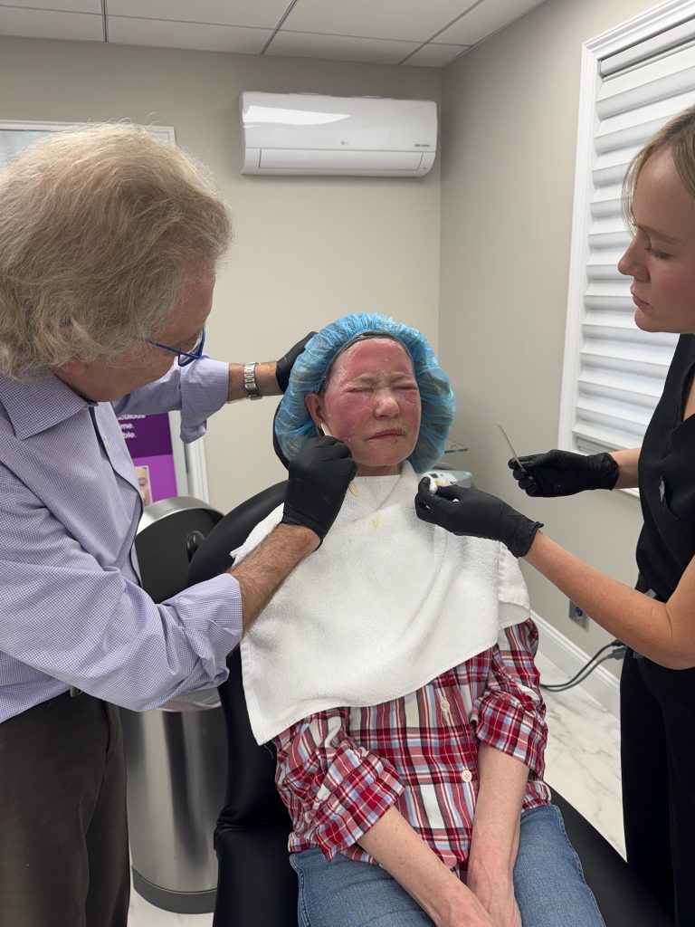 Leah Bueneman, PA-C, assists Dr. Richard Bensimon during a croton oil peel procedure as he applies the final layer of oil to the patient’s face.