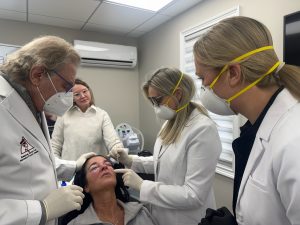 Dr. Beth Collins and Leah Bueneman, PA-C being trained on how to apply a croton oil peel by Dr. Richard Bensimon.