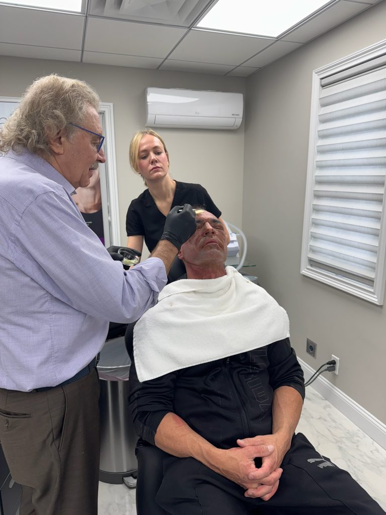 Leah Bueneman, PA-C, watches as Dr. Richard Bensimon applies layers of croton oil to a patient’s face to treat deep lines and wrinkles.